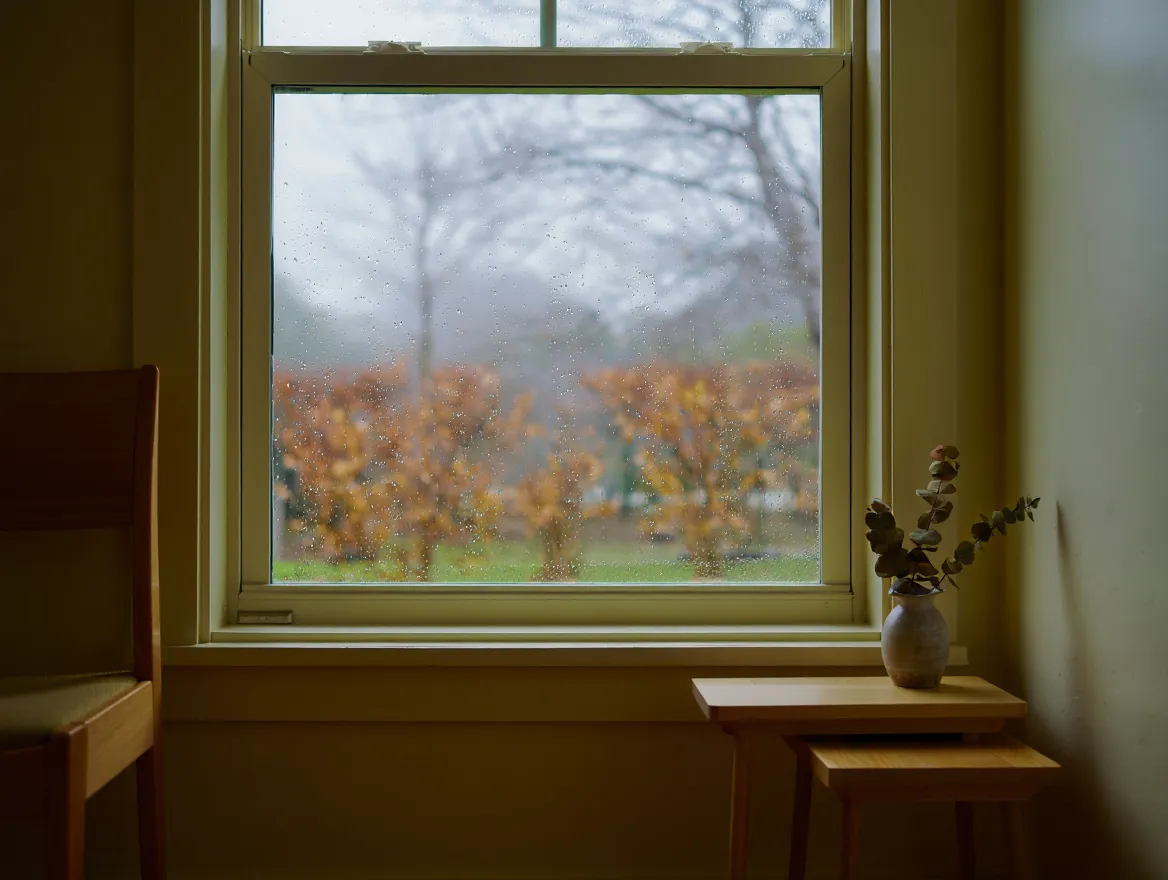 Person gently stretching arms at a bright, tidy desk with natural light